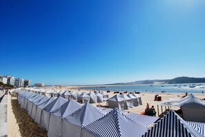 A beach with striped beach tents and a sandy shore.