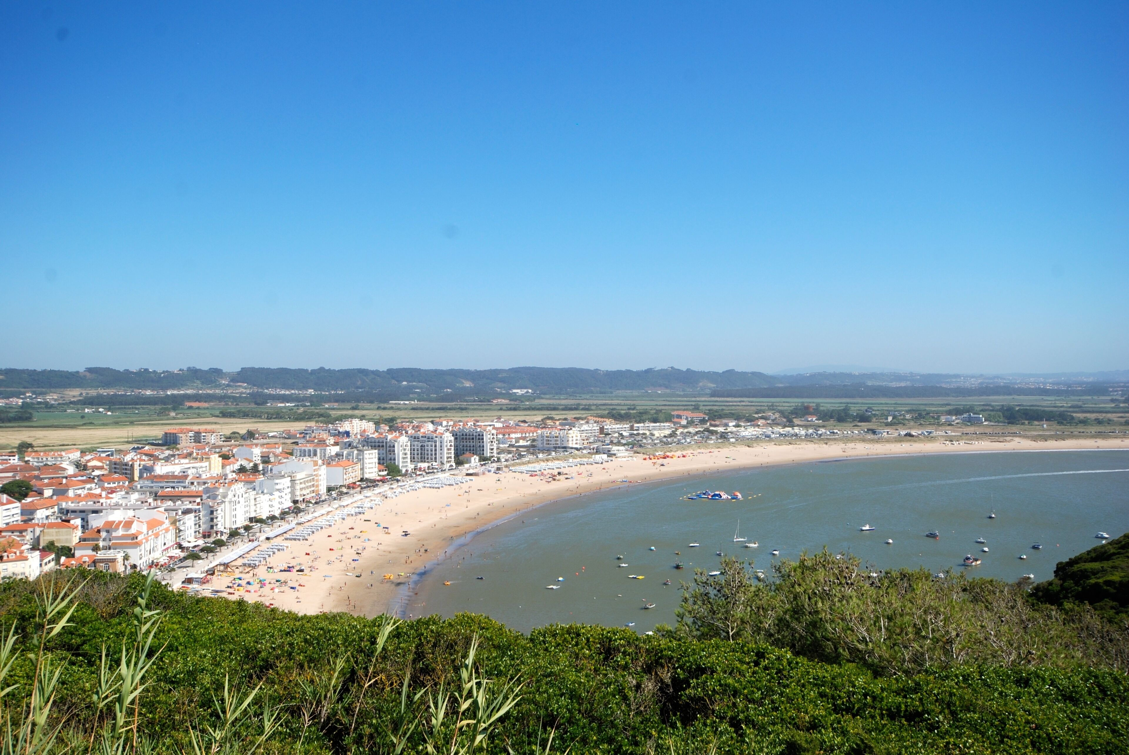 A coastal cityscape with a beach, buildings, and boats.