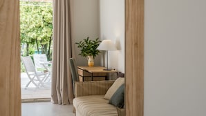 A room with a sofa, a small table with a lamp and a plant, and a view of an outdoor area with a table and chairs. - Tenuta DonnAnna (Galatone)