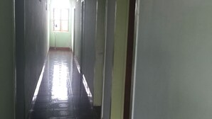 Un pasillo estrecho y bien iluminado, con suelo de baldosas y puertas a ambos lados que dan a habitaciones.