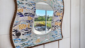 Specchio a mosaico con motivo geometrico, montato su una parete di legno bianco.