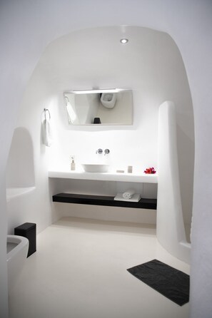 A modern bathroom with a white sink, mirror, and black towel holder. - Aleria Luxury Cave (private pool)  (Santorini)