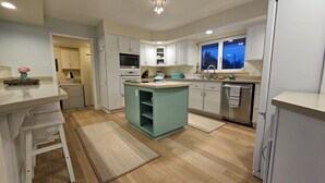 Una cocina moderna con armarios blancos, una isla central y un ventanal con vistas.