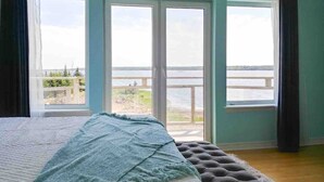 Un dormitorio con una cama grande, vista a un cuerpo de agua y un balcón.