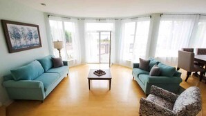 Un amplio salón con dos sofás, un sillón estampado y una mesa de centro.