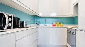 A modern kitchen with white cabinets, a microwave, a toaster, and a sink.