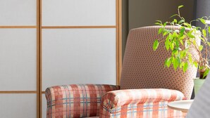 Una habitación con una puerta corredera tradicional, un sofá estampado de pata de gallo y una planta en maceta.