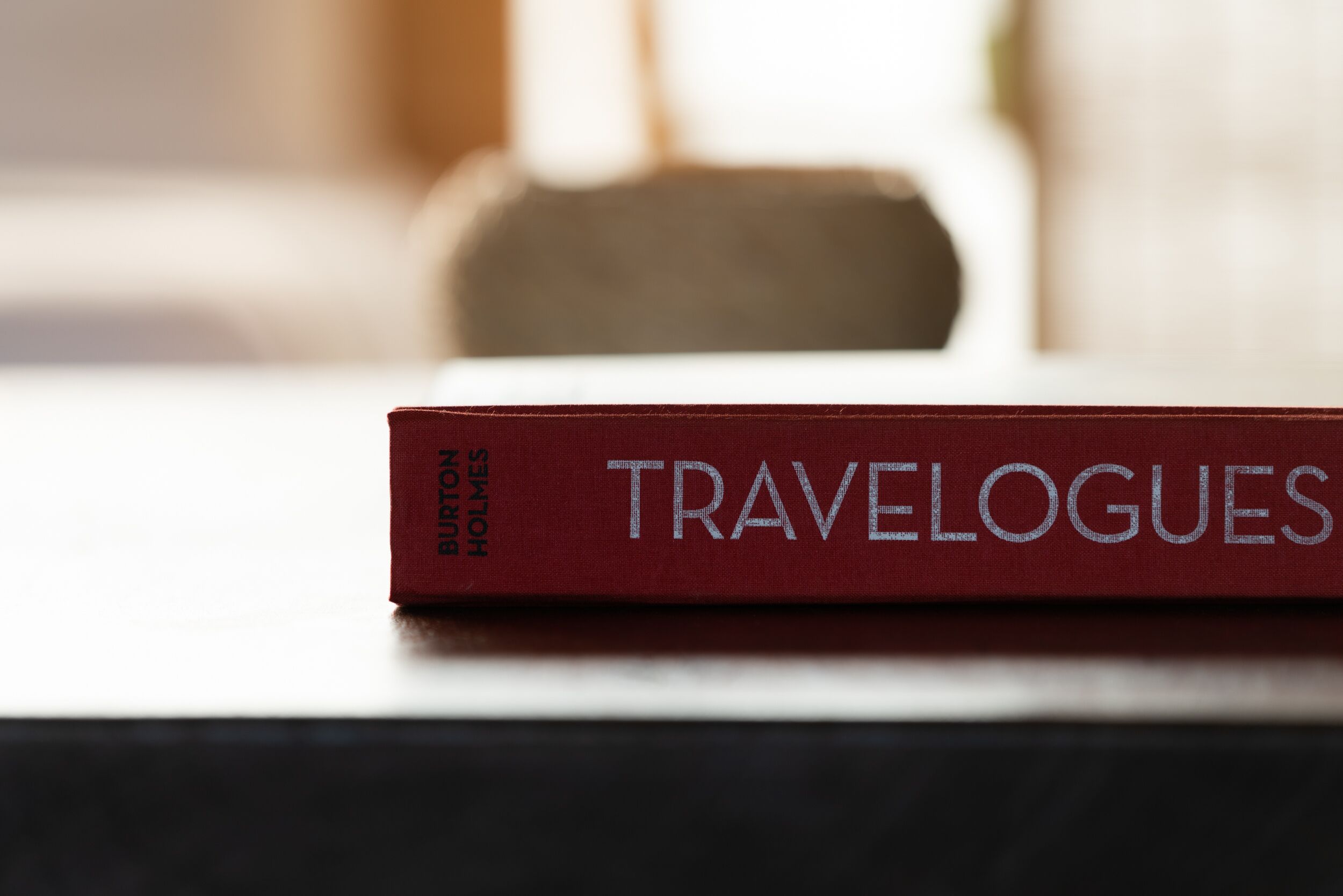 A red book titled "TRAVELOGUES" by BURTON HOCKLEY on a table.