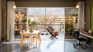 Un espacio de estar moderno con comedor, zona de trabajo y balcón con vista a la ciudad.