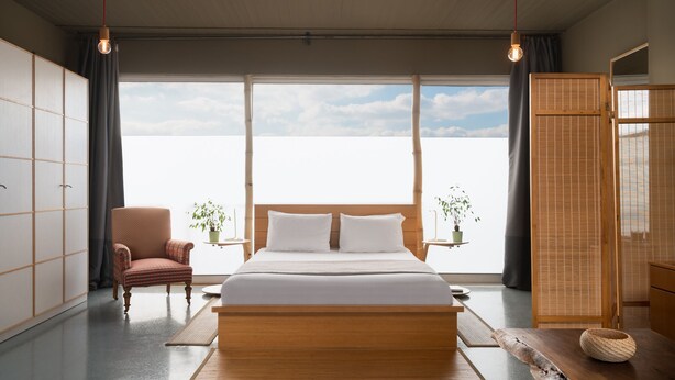 Un dormitorio moderno con una cama grande, una silla y vistas al cielo.