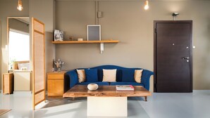 Una sala de estar moderna con un sofá azul, una mesa de centro de madera y una puerta oscura.
