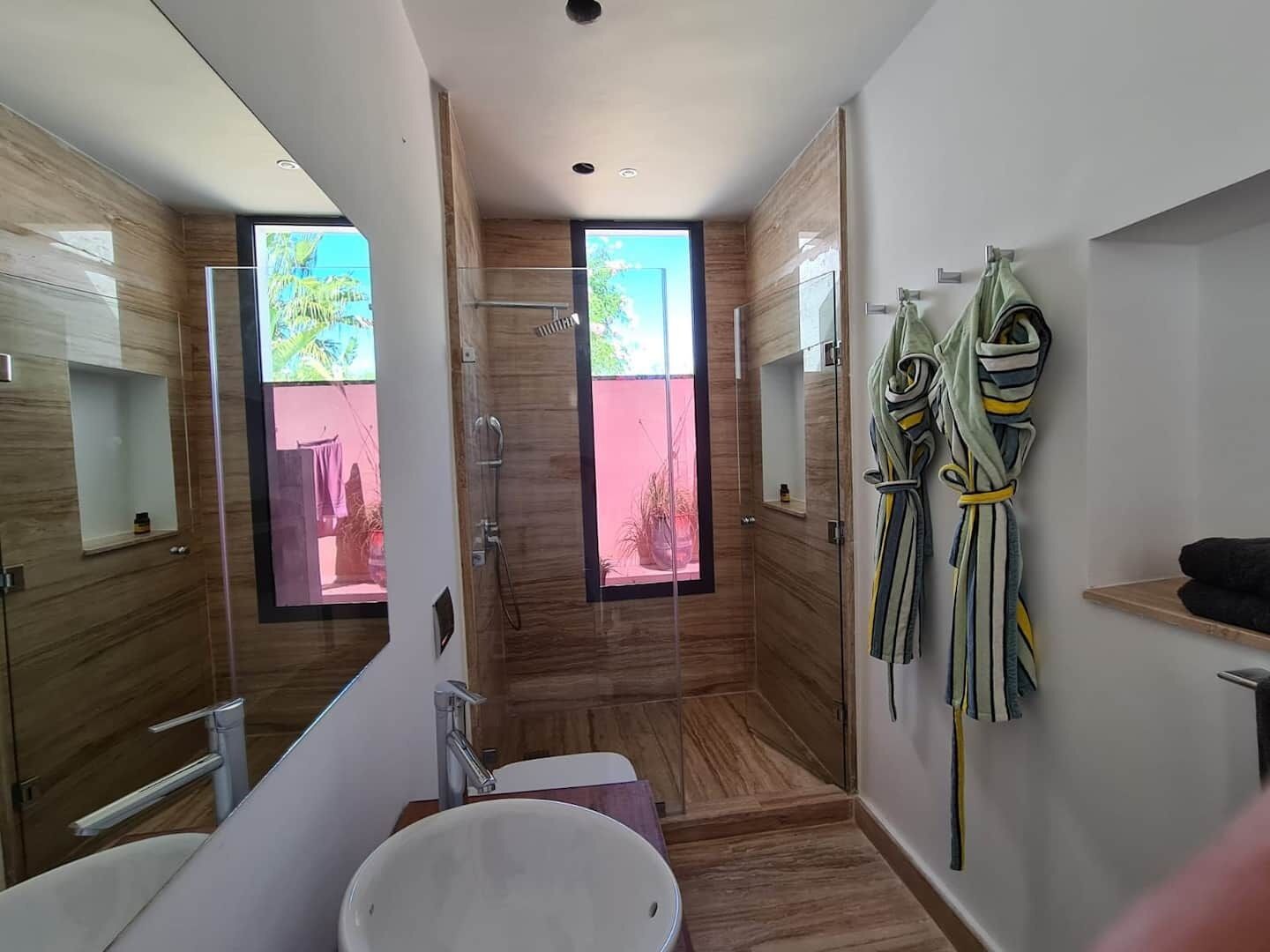 A modern bathroom with a large mirror, a sink, and a shower.