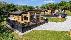 A row of wooden cabins with outdoor patios, a gravel driveway, and a car parked nearby.