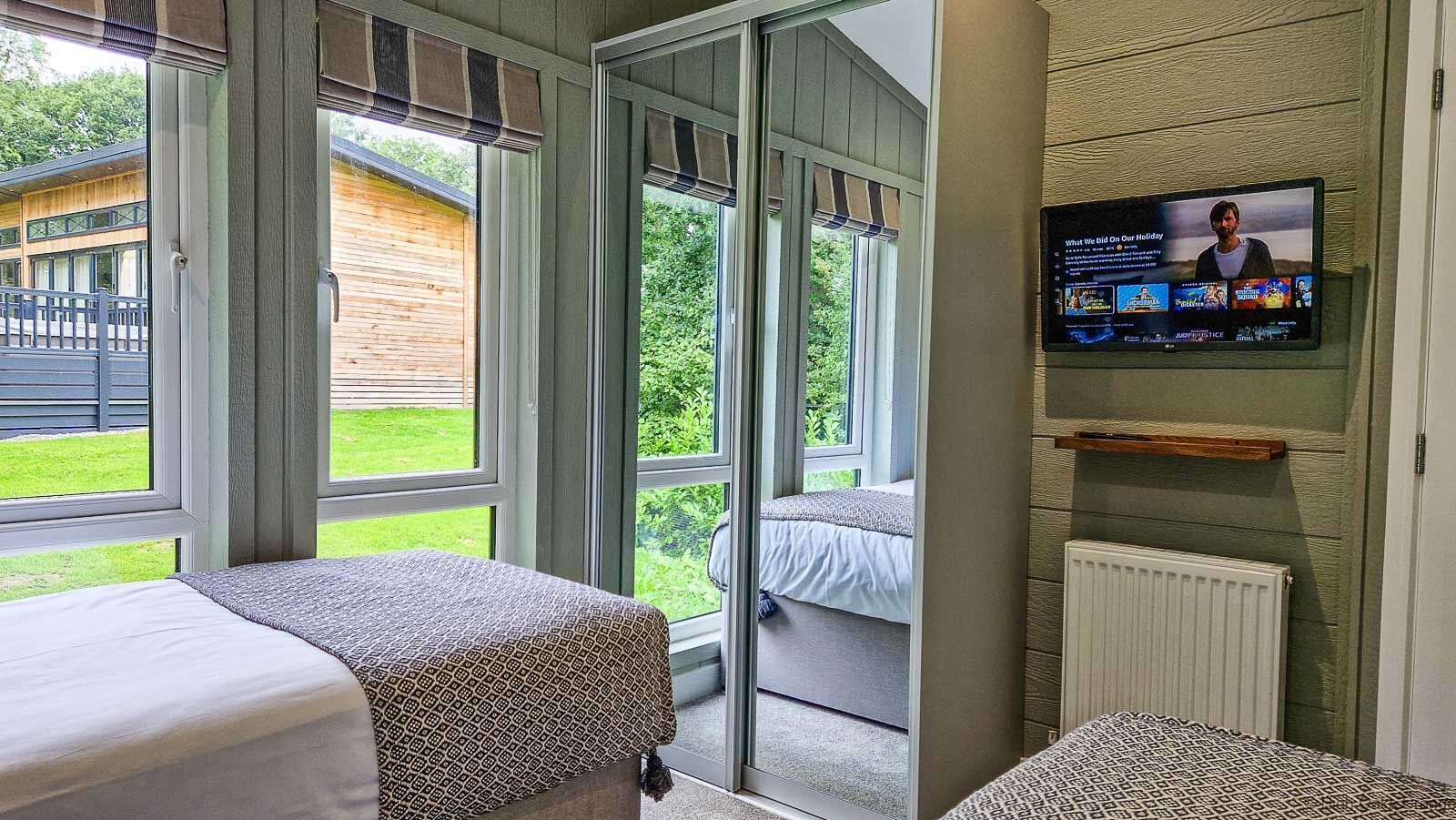 A hotel room with a bed, a TV mounted on the wall, and a sliding glass door leading to an outdoor area.