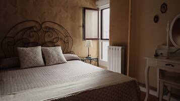 A bedroom with a bed, a dresser, a mirror, and a window.