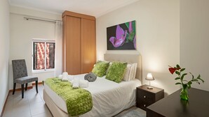 A bedroom with a bed, a chair, a nightstand, a lamp, and a painting. - In pedestrianised Funchal Old Town | Taberna Apt 2 (Funchal)
