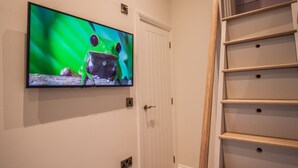 A television mounted on a wall displaying a frog, a white door, and a wooden shelf unit.