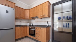 A kitchen with wooden cabinets, a stainless steel refrigerator, a built-in oven, and a microwave. - Villa Dulce Vista - 3 bedrooms, Heated Private Pool, with Mountain Views (Playa Blanca)