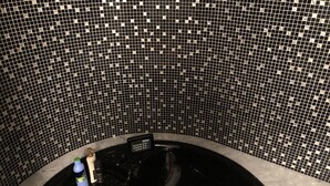 Een zwart bubbelbad met bedieningspaneel en een fles shampoo.