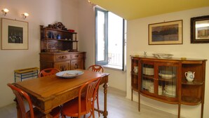 Une salle à manger avec une table et des chaises en bois, une fenêtre donnant sur un beau paysage et un buffet en verre.