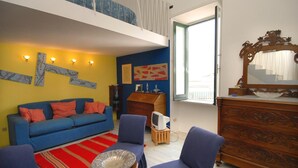 Un salon avec un canapé bleu, deux fauteuils, une commode en bois et un meuble pour la télévision.