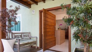 Una puerta de madera que da a una habitación con un banco y plantas en macetas.