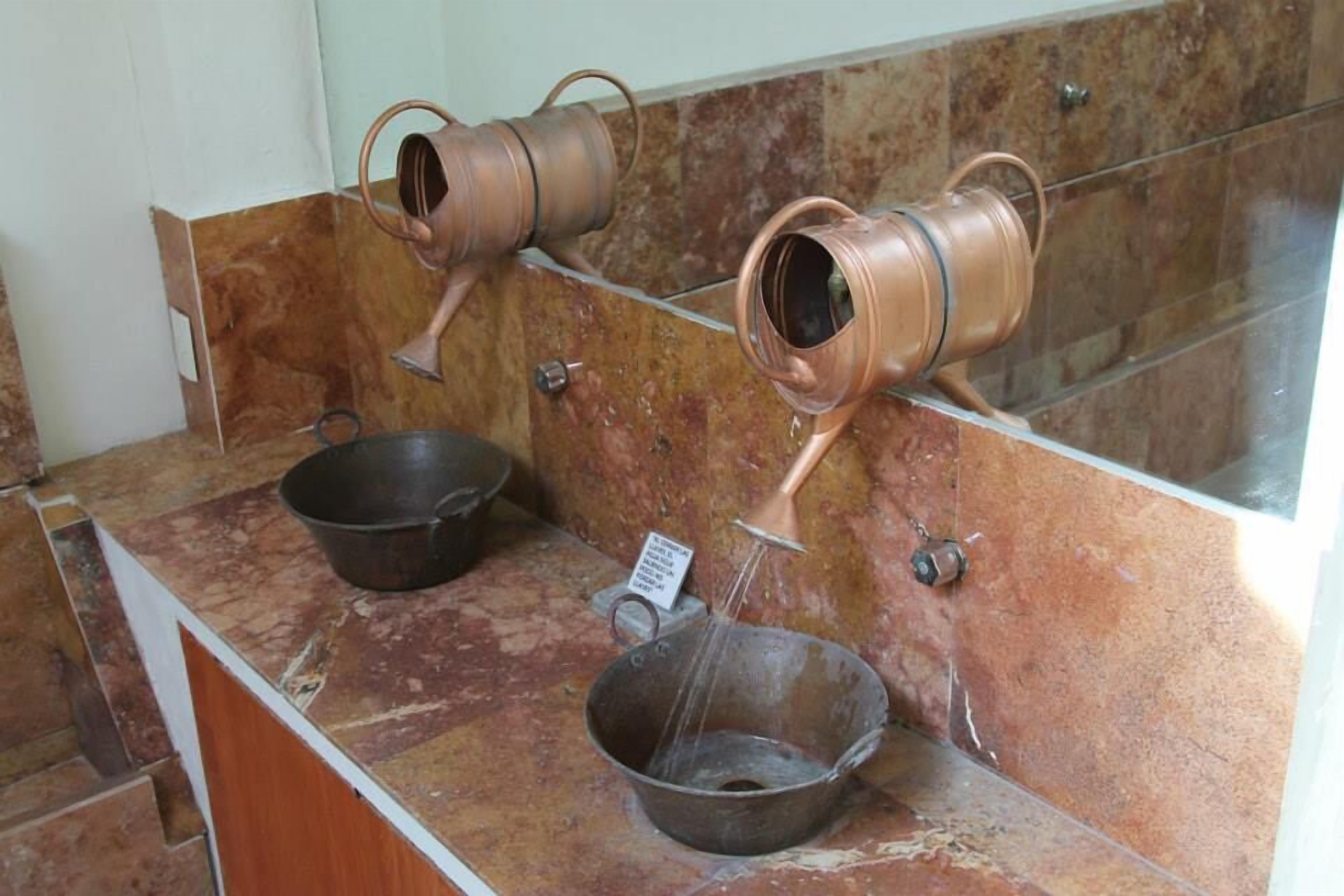 A bathroom with a marble countertop, two copper sinks, and a mirror.