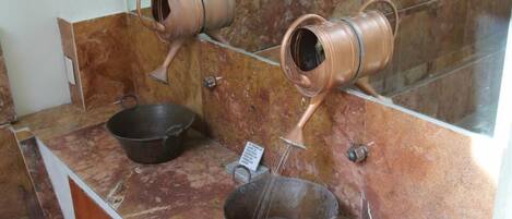 Un baño con encimera de mármol, dos lavamanos de cobre y un espejo.