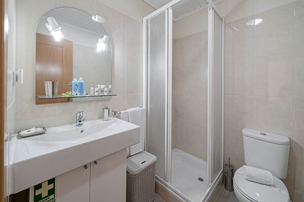 A modern bathroom with a glass shower enclosure, a white sink with a mirror, and a toilet.