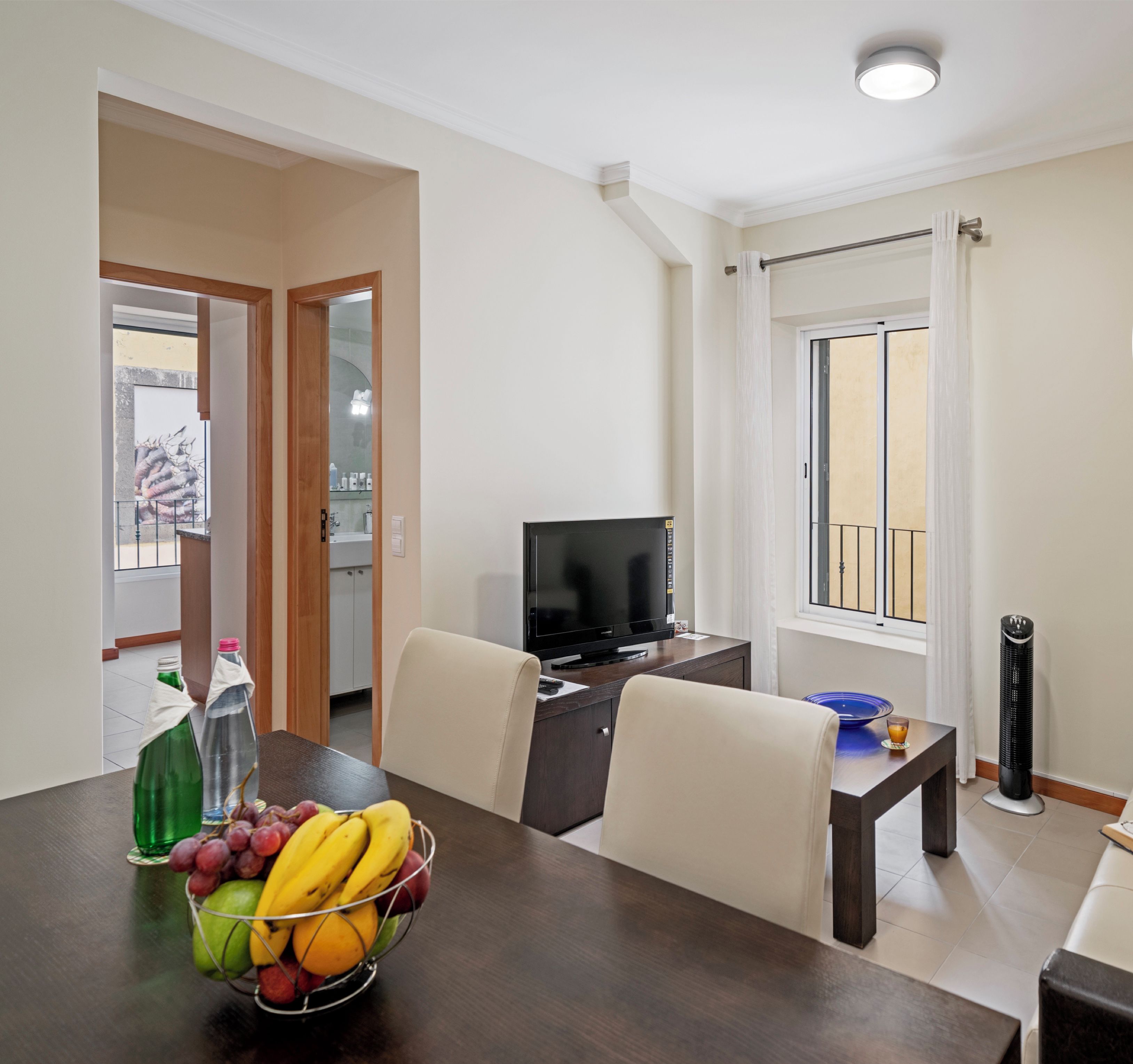 A modern living room with a dining area, a TV, and a balcony.
