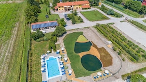 Eine Vogelperspektive eines Hotels mit Schwimmbad, Liegestühlen und einem großen Gebäude mit Solaranlagen.