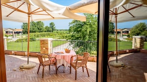 Eine Terrasse mit Tisch und Stühlen, Blick auf einen Garten und ein Zaun.