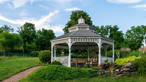 A gazebo with a covered seating area and a stone wall. - The Shepherd's Inn (Washington)
