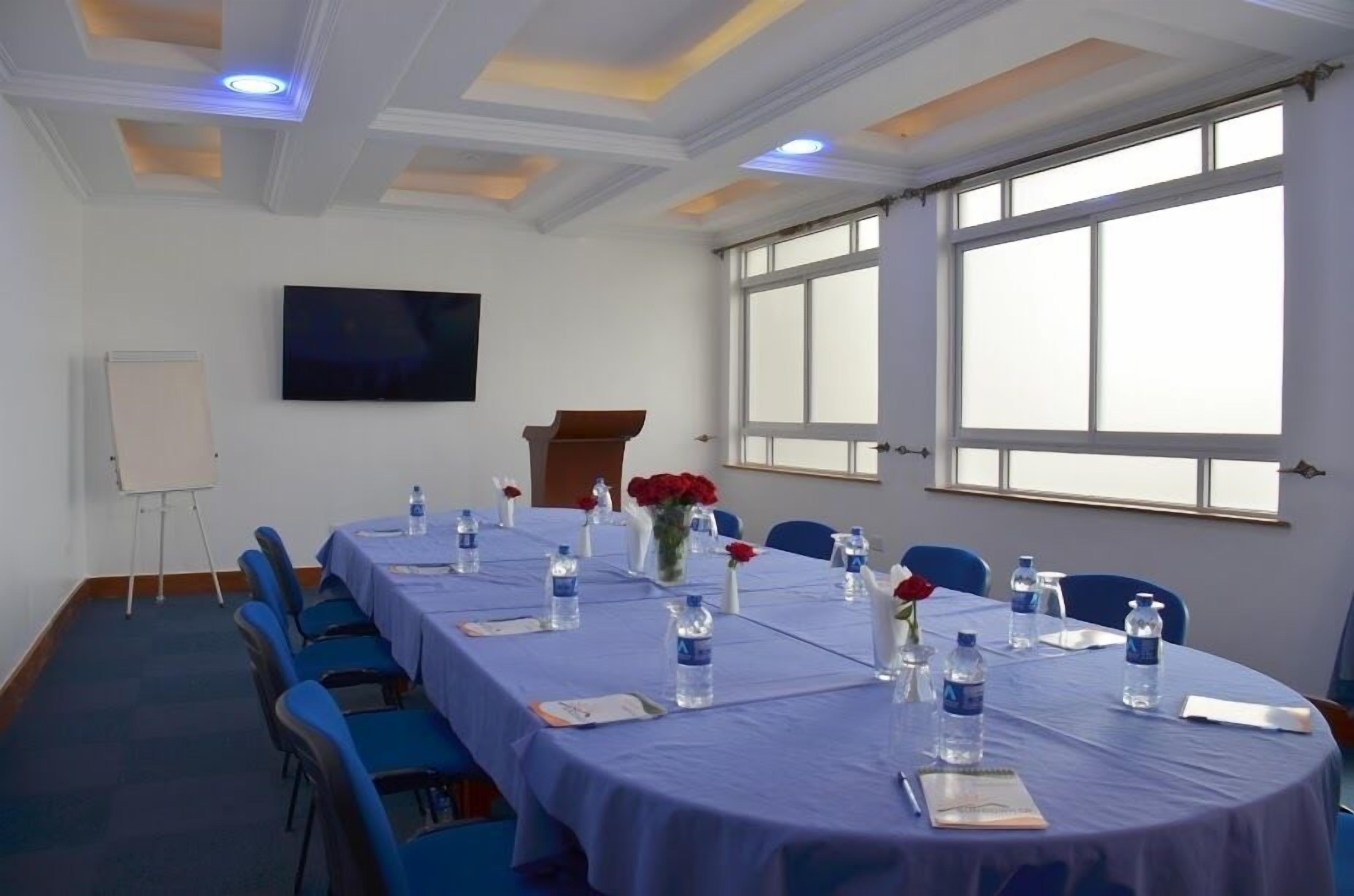 A conference room with a long table, chairs, water bottles, and a whiteboard.