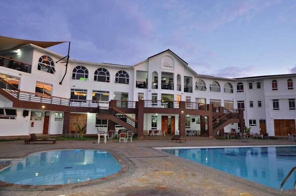 A multi-story hotel with a swimming pool, outdoor seating, and a staircase connecting the levels. - Greenpark Sundowner Hotel (Athi River)