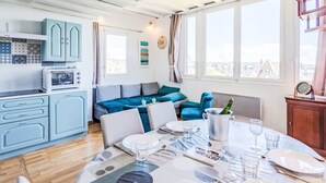 Eine moderne Küche mit integriertem Mikrowellenherd, einem Essbereich für vier Personen mit Tisch und Stühlen, und Blick auf die Stadt durch große Fenster.