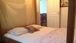 A single bed with a wooden frame, white bedding, and a brown pillow.