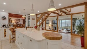 A spacious kitchen with a large island, wooden beams, and pendant lighting.