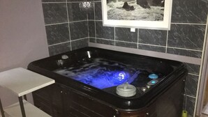 Un jacuzzi noir doté d’un panneau de commande et d’une petite table placée à côté.