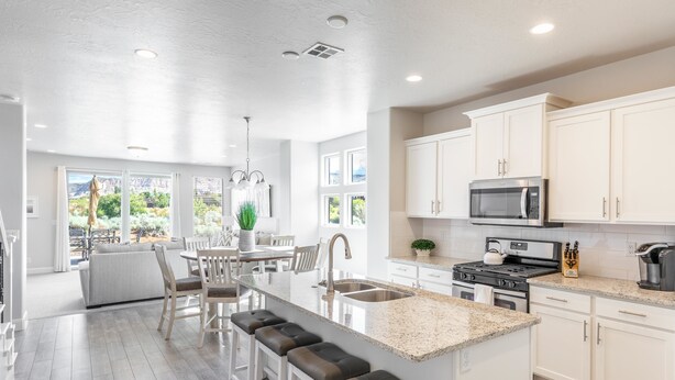 A spacious kitchen with white cabinets, a granite countertop, and a central island with bar stools.