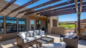 An outdoor patio with wicker furniture, a pergola, and a view of the landscape.
