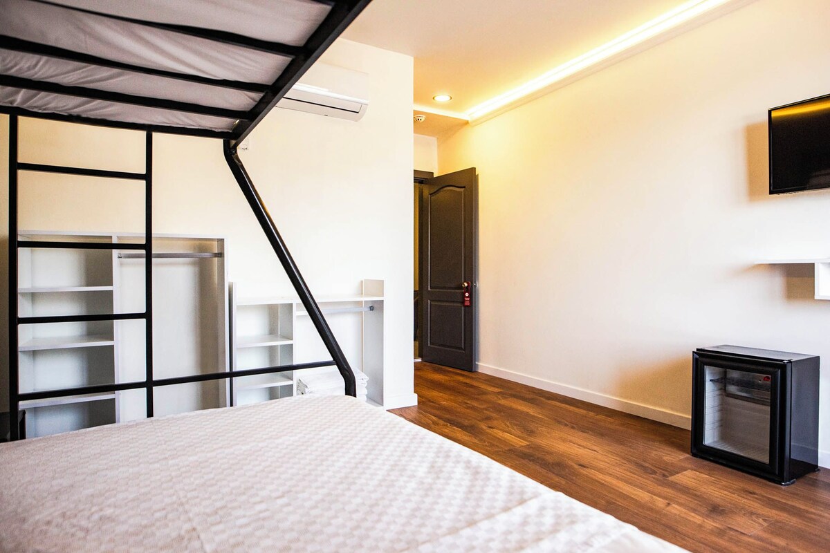 Une chambre comprenant un lit, une armoire intégrée, un petit réfrigérateur noir et un téléviseur fixé au mur.