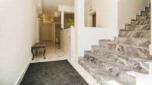 Een hal met een marmeren trap die naar een kamer leidt.
