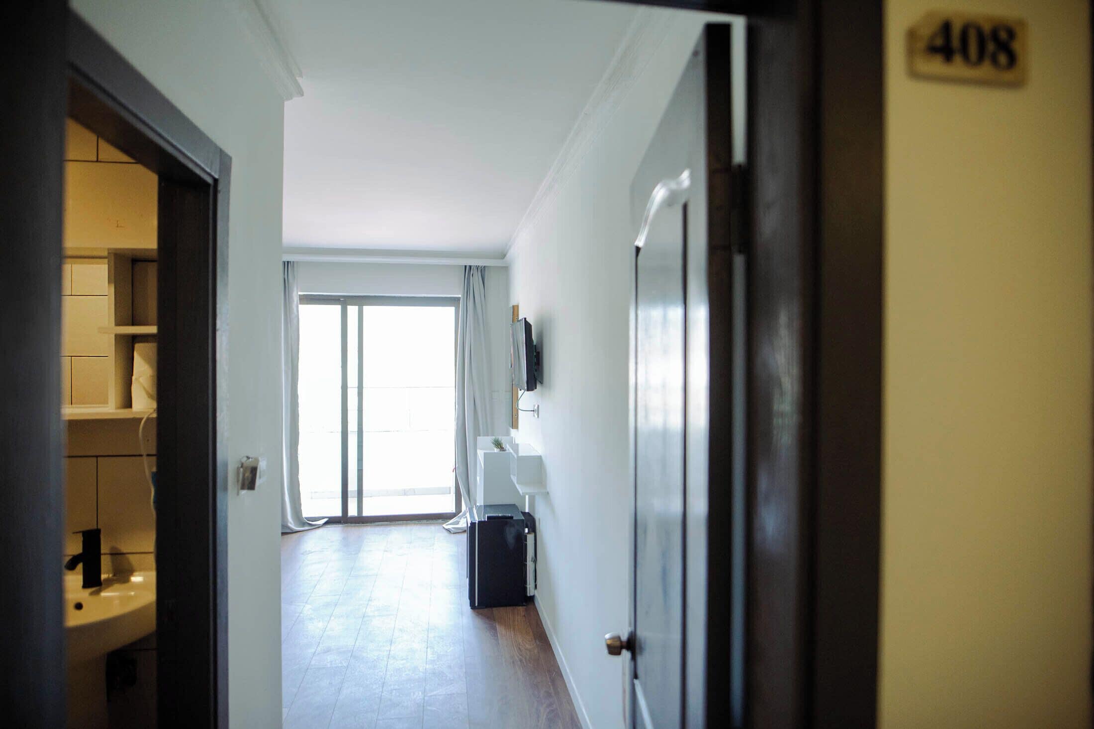 A hallway with a door labeled 408, leading to a room with a window and a view of the outdoors.