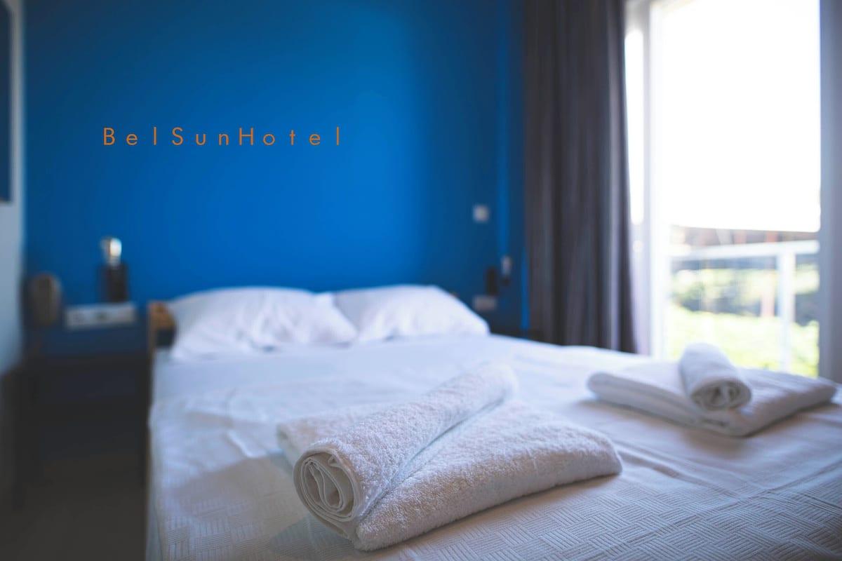 Une chambre d’hôtel avec un lit, des serviettes blanches et un mur bleu.
