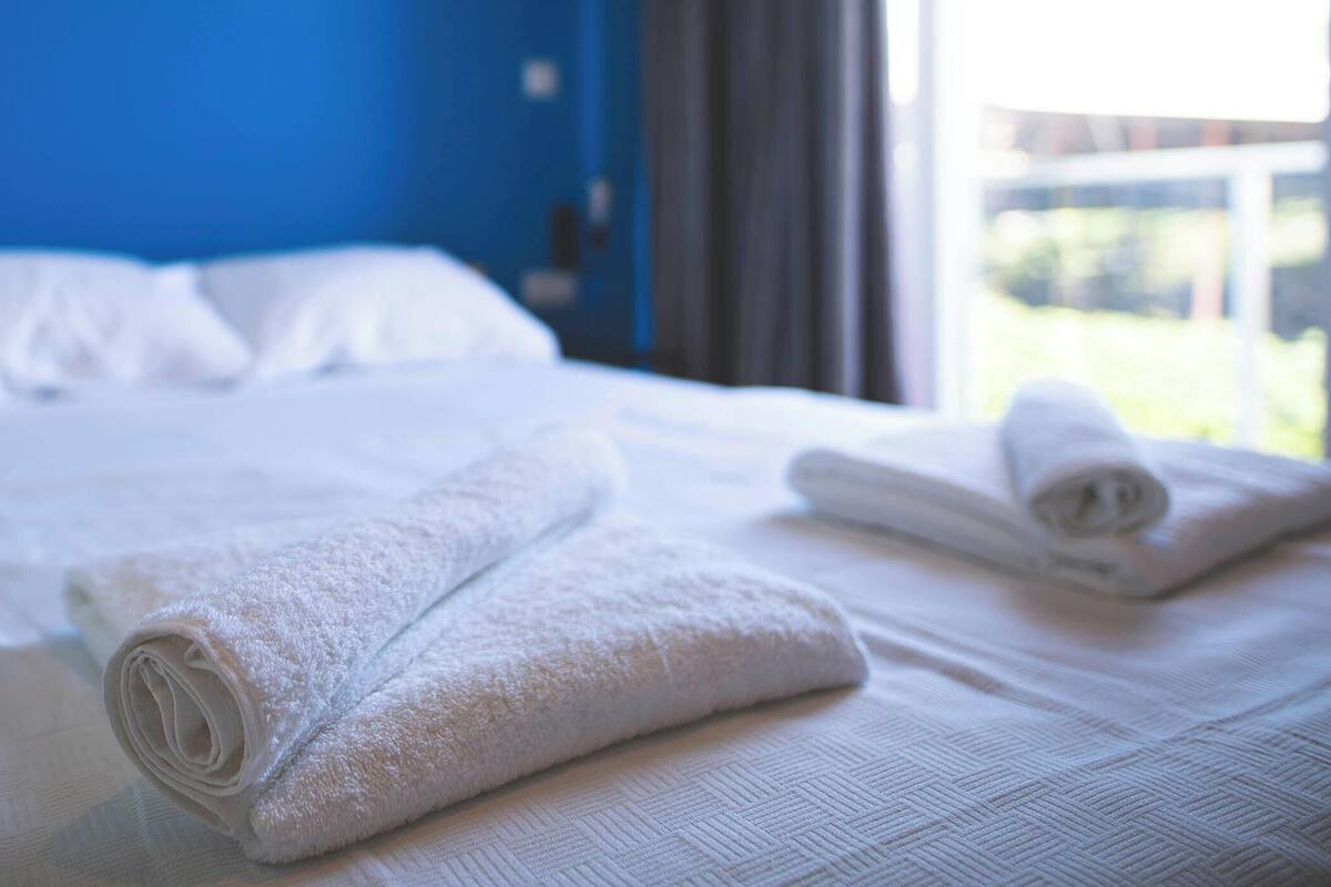 Ein Hotelzimmer mit einem Bett, weißen Handtüchern und einer blauen Wand.