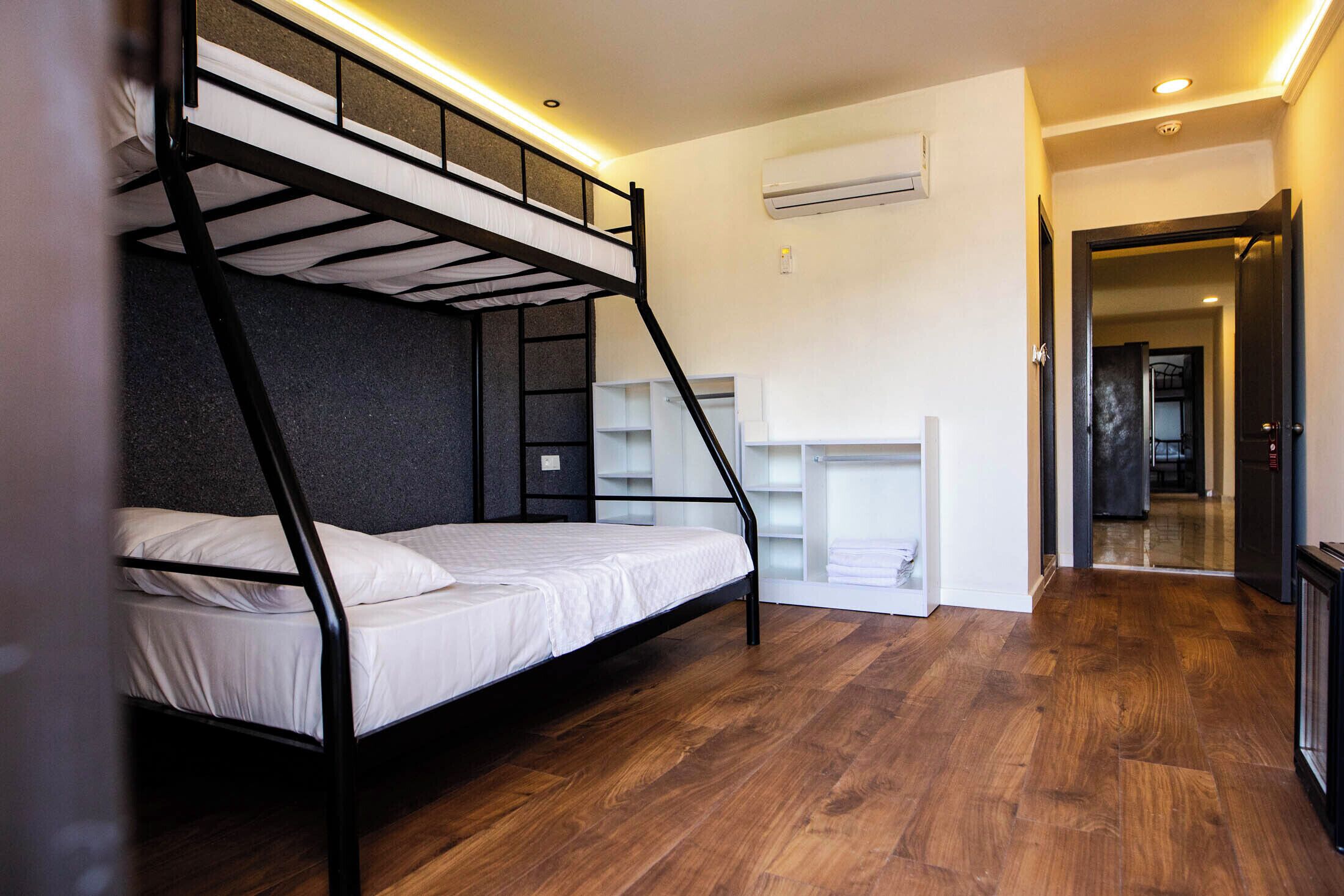 Une chambre avec un lit superposé, un plancher en bois, des murs blancs et une armoire intégrée.