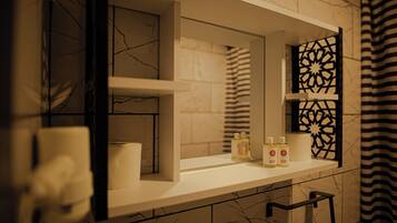 A bathroom with a white vanity, a mirror, and a decorative black and white geometric panel.