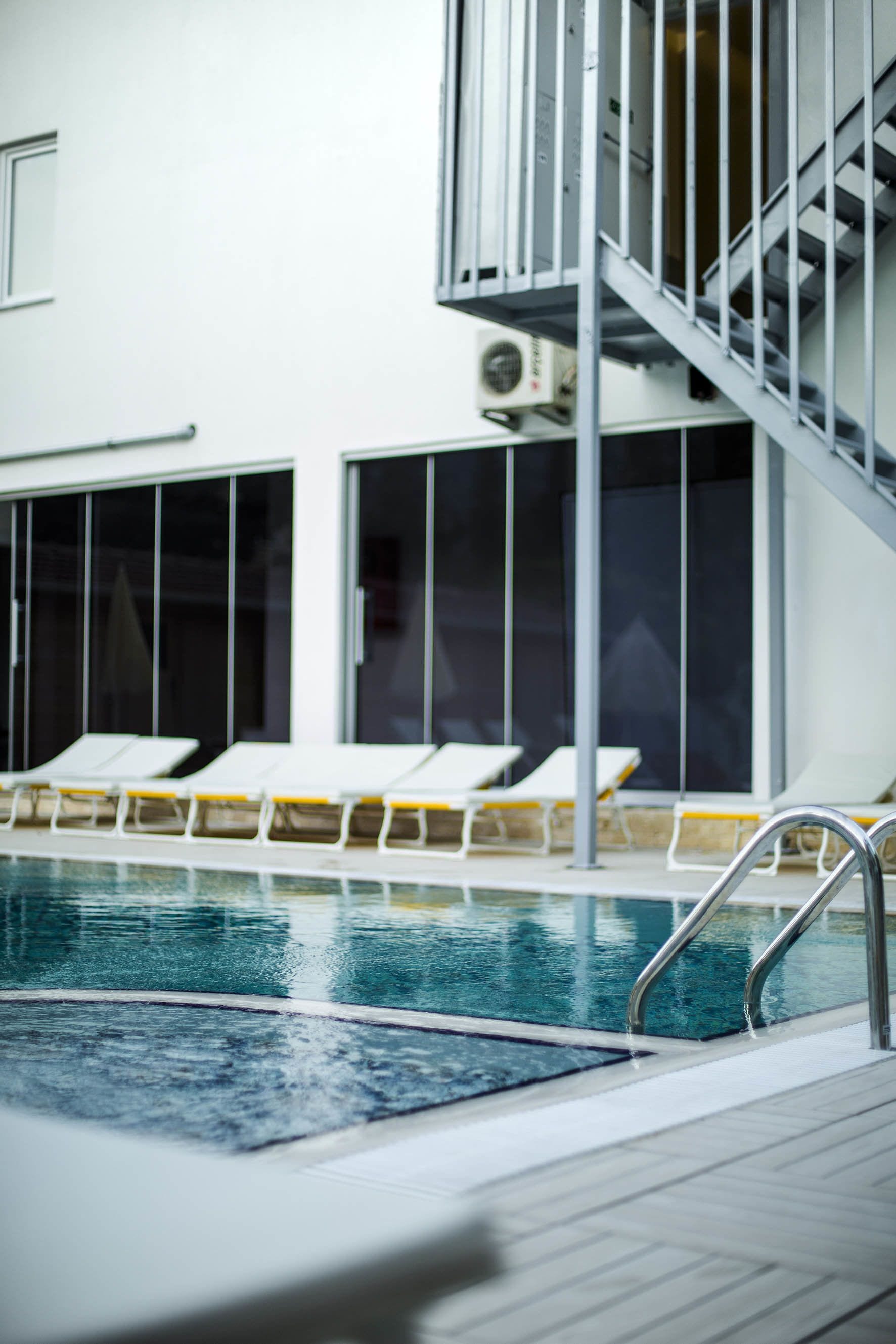 A pool area with lounge chairs and a staircase.