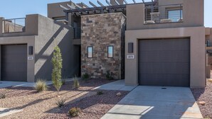 A modern two-story building with a stone facade, a covered outdoor seating area, and a garage. - Desert Solace (St. George)